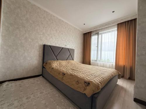 a bedroom with a bed and a large window at Novel apartment in Korumdy