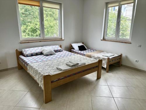 two beds in a room with two windows at Anit Rooms in Luštica