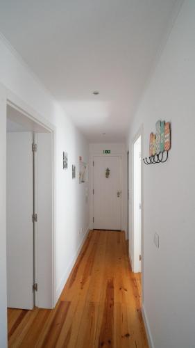 an empty living room with white walls and wooden floors at Apartamentos Aurea - Sesimbra in Sesimbra