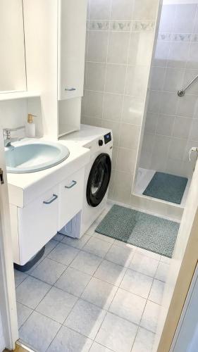 a white bathroom with a sink and a washing machine at L'Arletta in Saint-Cyprien-Plage