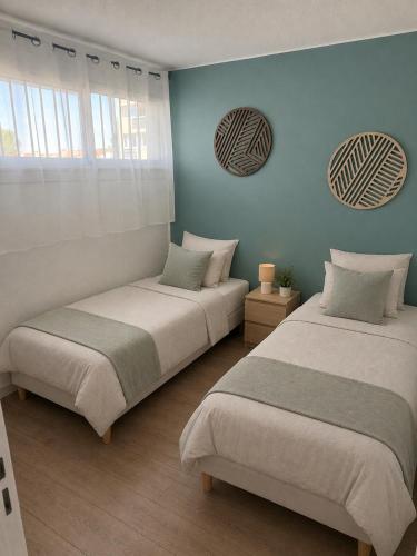 two beds in a room with blue walls and windows at L'Arletta in Saint-Cyprien-Plage