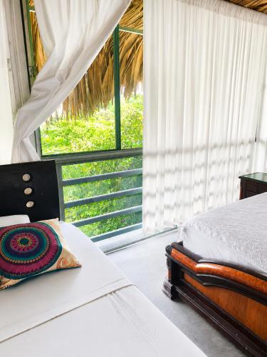 a bedroom with a bed and a large window at Huiltana ecohotel&resort in Guataquí