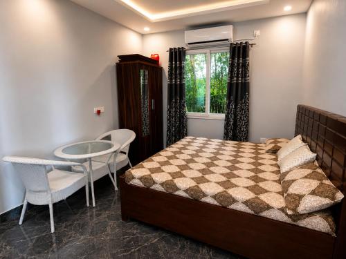 a bedroom with a bed and a table and chairs at Vijay Laxmi Farm House in Manjhāoli