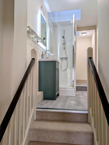 a bathroom with a sink and a shower and stairs at SixCheapStreet in Newbury