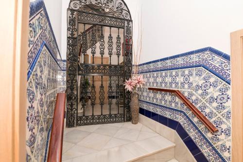 a staircase with a gate with blue and white tiles at Hostal Colón Don Miguel in Cádiz