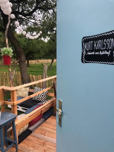 a sign on a deck with a table and a tree at Bauwagen im Apfelgarten in Winsen