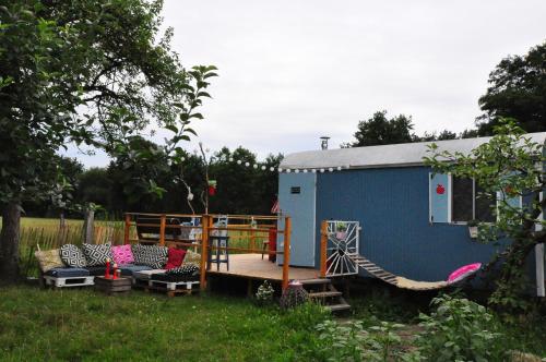 a blue shed with a porch and chairs and a hammock at Bauwagen im Apfelgarten in Winsen