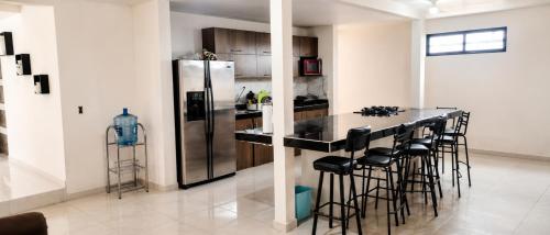 a kitchen with a refrigerator and a bar with stools at Casa Oasis Aguascalientes in Cañada del Rodeo