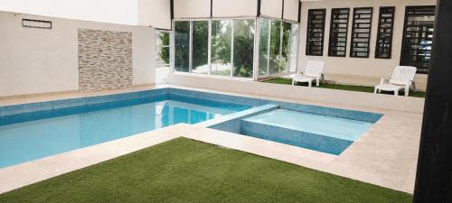 a swimming pool in a house with two chairs at Casa Oasis Aguascalientes in Cañada del Rodeo