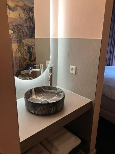 a bathroom with a stone sink and a mirror at Gilded Ox Suites in Deventer