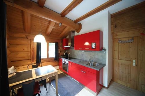 a kitchen with red cabinets and a sink and a table at Le Gîte de Briey - Chalet complet in Chalais