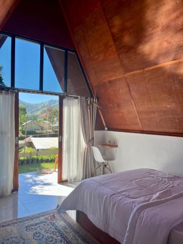 a bedroom with a bed and a large window at Roman Villa Syariah in Sembalun Lawang