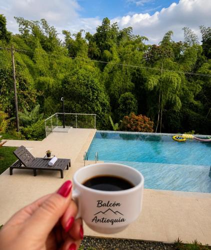a woman holding a cup of coffee next to a pool at Balcón de Antioquia Exclusiva Villa Campestre con Piscina Privada, Jacuzzi y BBQ en el Eje Cafetero, cerca del Parque del Café in Montenegro