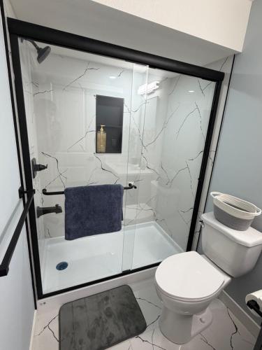 a bathroom with a toilet and a glass shower at Entire 2BR Suite 12 min to Airport in Calgary