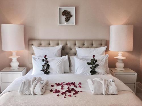 a bed with flowers on it with two lamps at The Glen Boutique Hotel & Spa in Cape Town