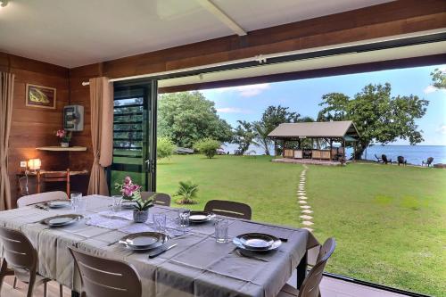a dining room with a table and a large window at Fare Heimery - Private Lagoon Beach in Haapiti