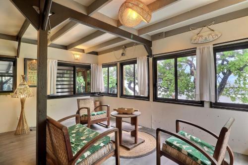 a living room with a table and chairs and windows at Fare Vainina Private beach - Golf in Moorea