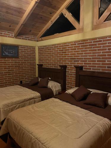 a room with two beds and a brick wall at Zidada Mundo Magico in Huasca de Ocampo