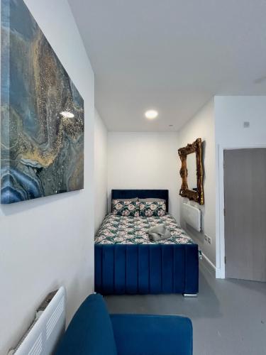 a bedroom with a blue bed and a painting on the wall at Cosy flat in central Cardiff Bay in Cardiff