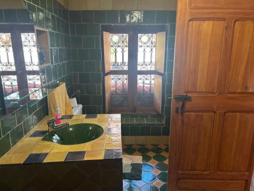 a bathroom with a green sink and a door at Kasbah Petit Nomade in Tinerhir