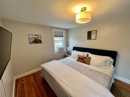 a bedroom with a bed with white sheets and a window at Inn on Willard in South Portland