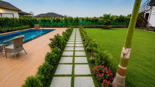 a garden with a swimming pool and a chair and flowers at Vijay Laxmi Farm House in Manjhāoli