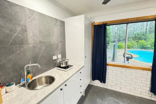 a kitchen with a sink and a large window at Pool House with 3 BDR 2 AC in Marsden