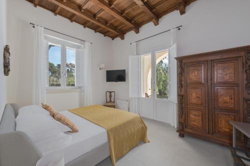 a white bedroom with a bed and a wooden cabinet at Villa Tuzzo in Lecce
