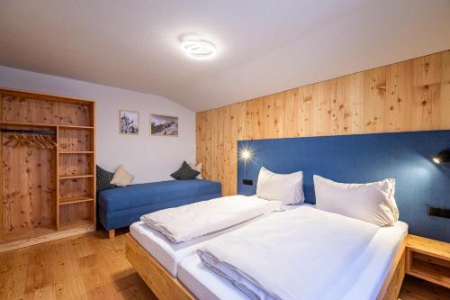 a bedroom with a large bed and a blue couch at DORFSTUDIO Apartments in Söll