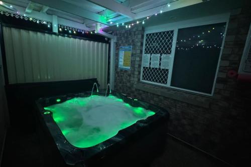 a dark bathroom with a green bath tub at SPA House 4 BDR 5 beds Master with AC) in Boronia Heights