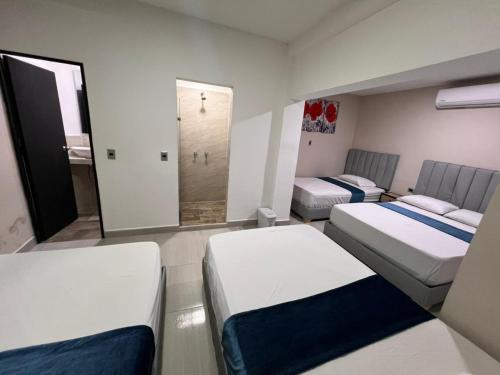 a room with three beds and a mirror at Hotel San Juan 70 Express Medellin in Medellín