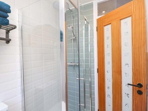 a shower with a glass door in a bathroom at Camellia Cottage in Wimborne Minster