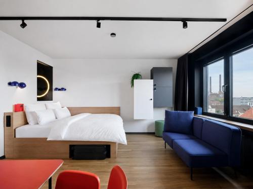 a bedroom with a bed and a blue couch at STAYERY Wolfsburg - VW Tor 17 in Wolfsburg