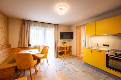 a kitchen with yellow cabinets and a table with chairs at DORFSTUDIO Apartments in Söll
