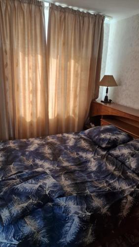 a bedroom with a bed and a window with curtains at Квартира1 in Balqash