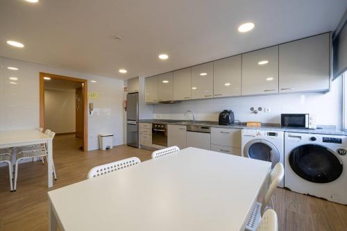 a kitchen with a washing machine and a table and chairs at Central Suítes 3 in São João da Madeira