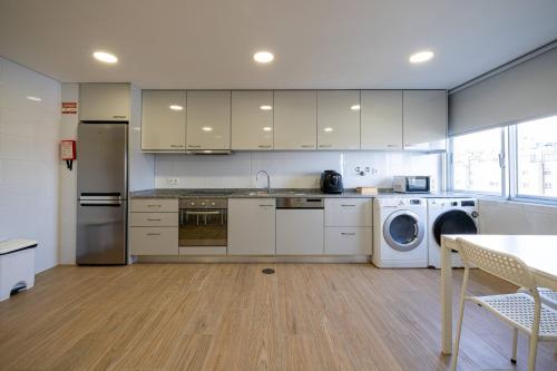 a kitchen with white cabinets and a washer and dryer at Central Suítes 3 in São João da Madeira