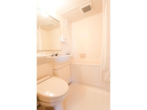 a white bathroom with a toilet and a sink at Smile Hotel Shiogama in Shiogama