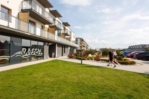 a man walking down a sidewalk in front of a building at MB Apartments z Basenem i Ogrodem in Sarbinowo