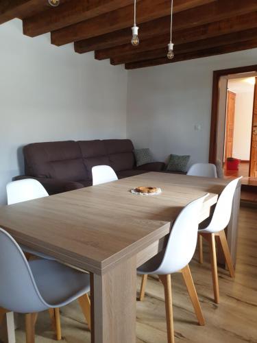 a dining room with a wooden table and white chairs at La Casa nel Sole in Savogna
