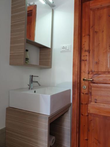a bathroom with a white sink and a wooden door at La Casa nel Sole in Savogna