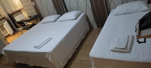 two beds in a small room with white sheets at Paraná Comfort Hotel in Cianorte