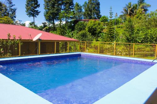 a large blue swimming pool with a fence and trees at Quinta La Carmencita in Santa Elena