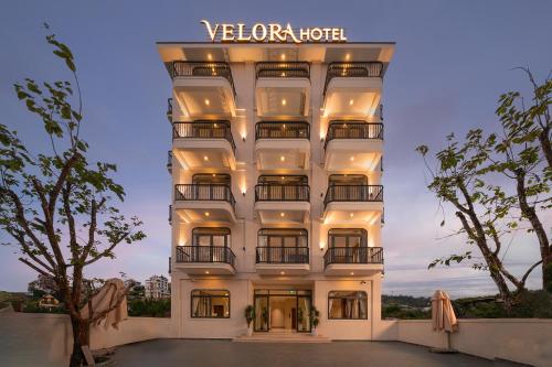 a tall white building with a sign on it at Velora Hotel DaLat in Xuan An