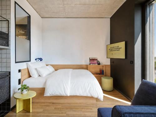 a bedroom with a white bed and a yellow table at STAYERY Gütersloh Hauptbahnhof & City Center - alle Zimmer mit Klimaanlage in Gütersloh