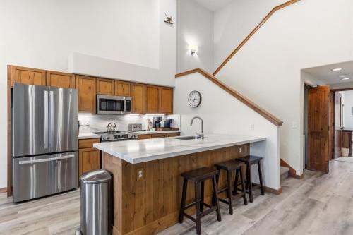 a kitchen with wooden cabinets and a stainless steel refrigerator at Los Pinos 22C by Great Western Lodging in Breckenridge