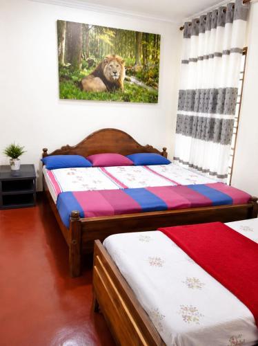 two beds in a bedroom with a lion on the wall at පසන් නිවස Pasan Niwasa Homestay Bandarawela in Bandarawela