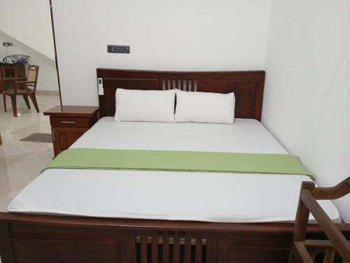 a bed with a wooden headboard and white sheets at East HOME Kalmunai in Kalmunai