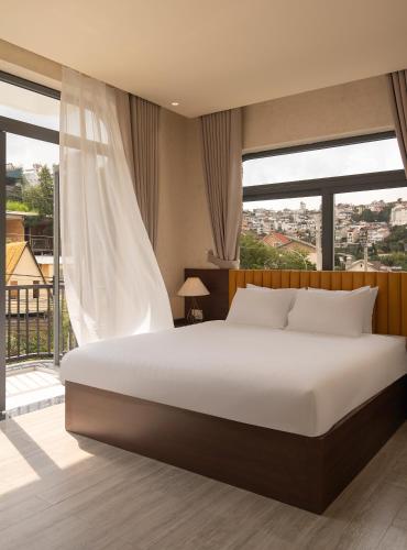 a bedroom with a large bed and a large window at Velora Hotel DaLat in Xuan An