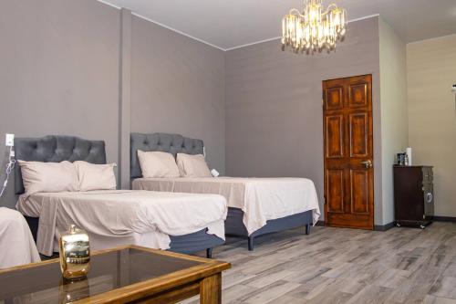 a bedroom with two beds and a table and a chandelier at Cozy Cabin in Cumbres del Nacimiento, La Unión Sur in Conchagua